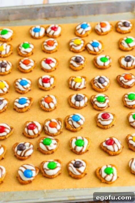 M&M's on melted Hershey Hugs on pretzels on a baking sheet.