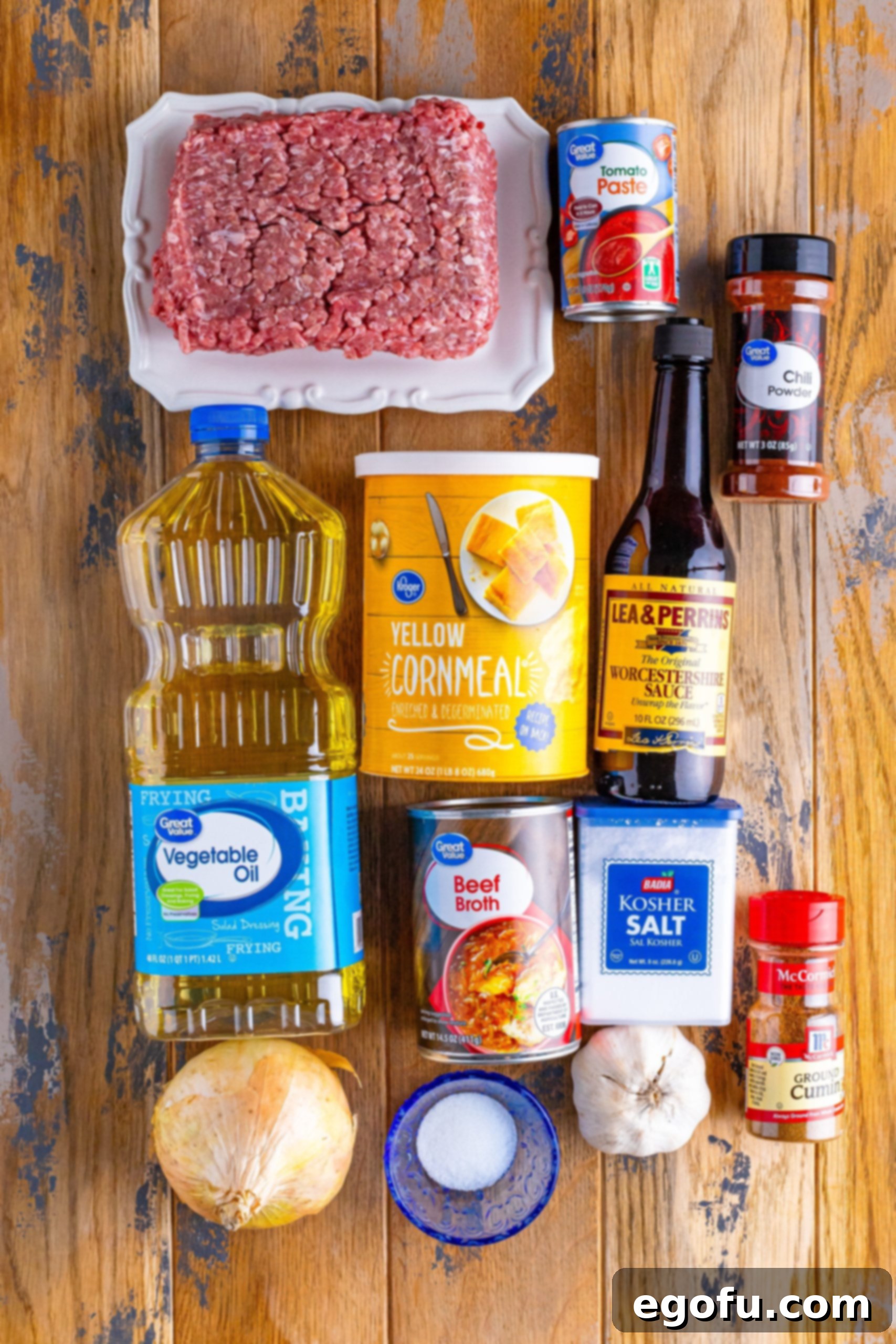 Onion, garlic, ground beef, chili powder, sugar, cumin, vegetable oil, corn meal, kosher salt, Worcestershire sauce, beef broth, and tomato paste. 