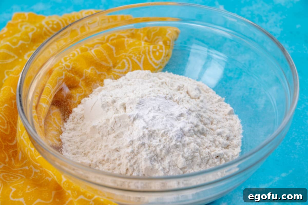 A bowl containing a mixture of flour and baking powder, ready for the Hot Milk Sponge Cake batter.