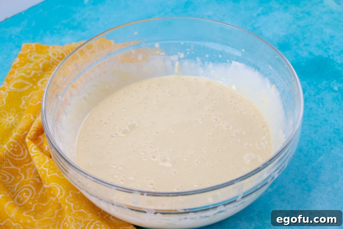 Hot Milk Sponge Cake batter in a bowl, showing the combined egg and flour mixture with a smooth consistency.