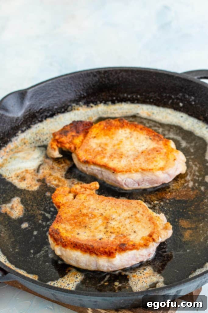 browned pork chops in a cast iron skillet.