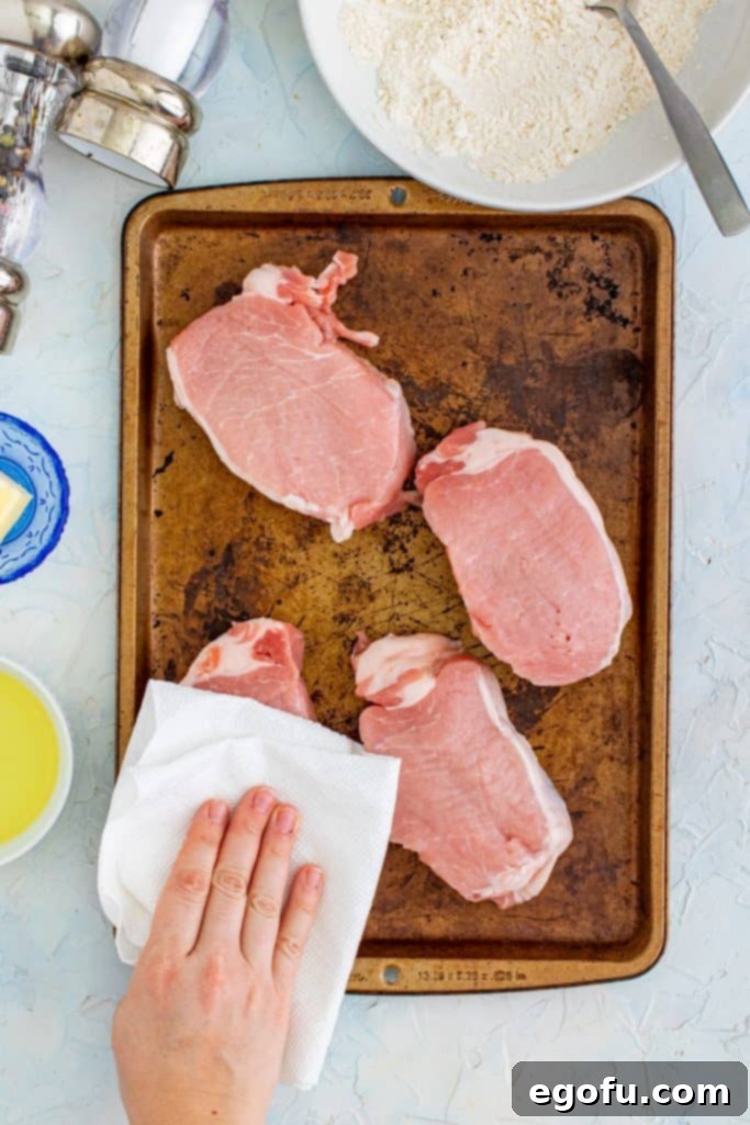 patting pork chops with a paper towel.