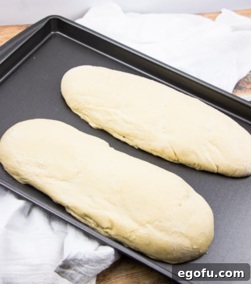 Effortless French Bread Baked Your Way 7 two French bread loaves rising on a large baking sheet.