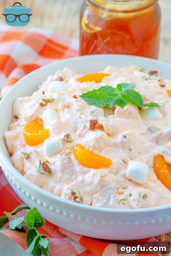 Orange Fluff dessert shown in a large white bowl, topped with fresh mint.