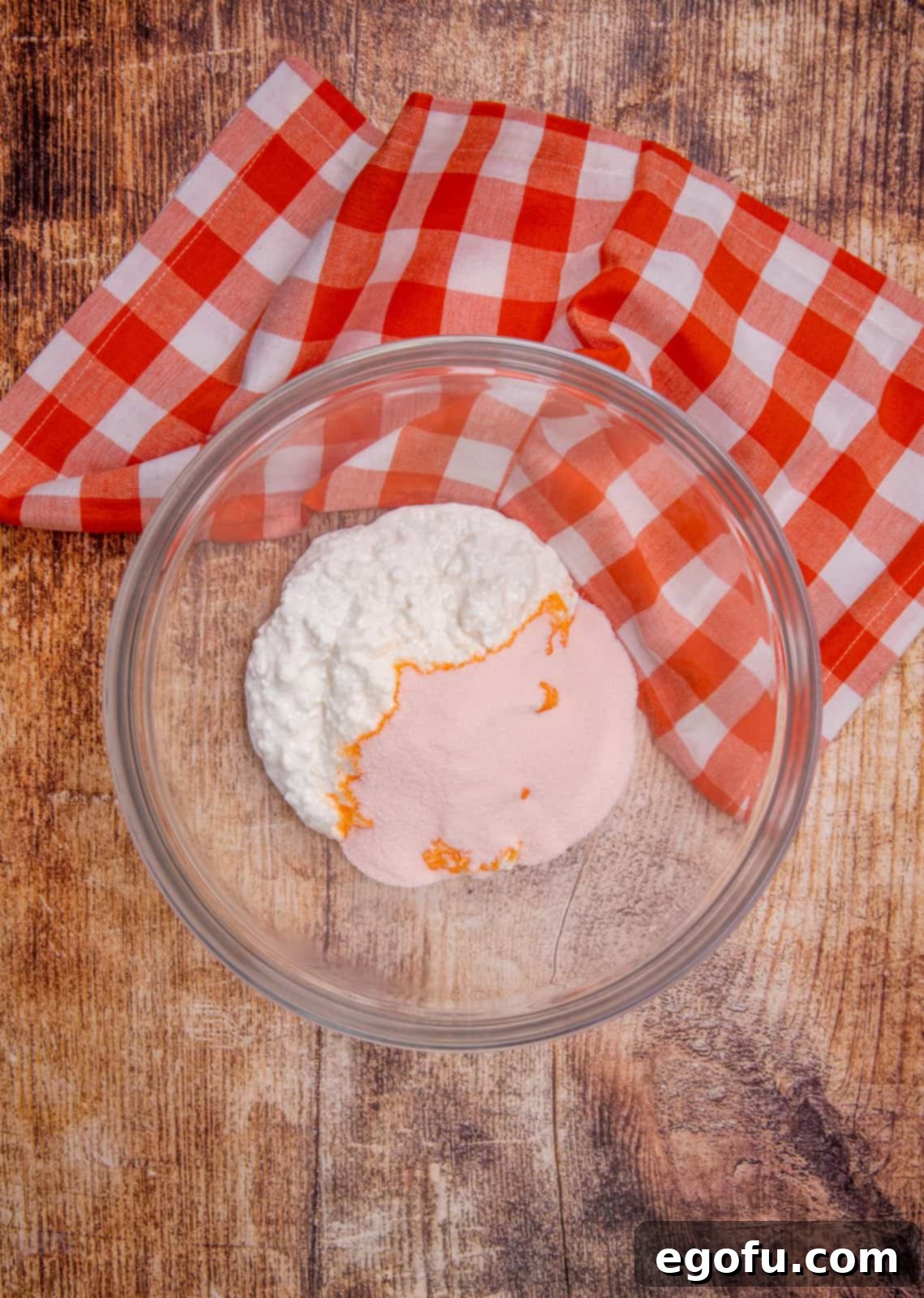 small curd cottage cheese and orange gelatin mix in a clear glass bowl.