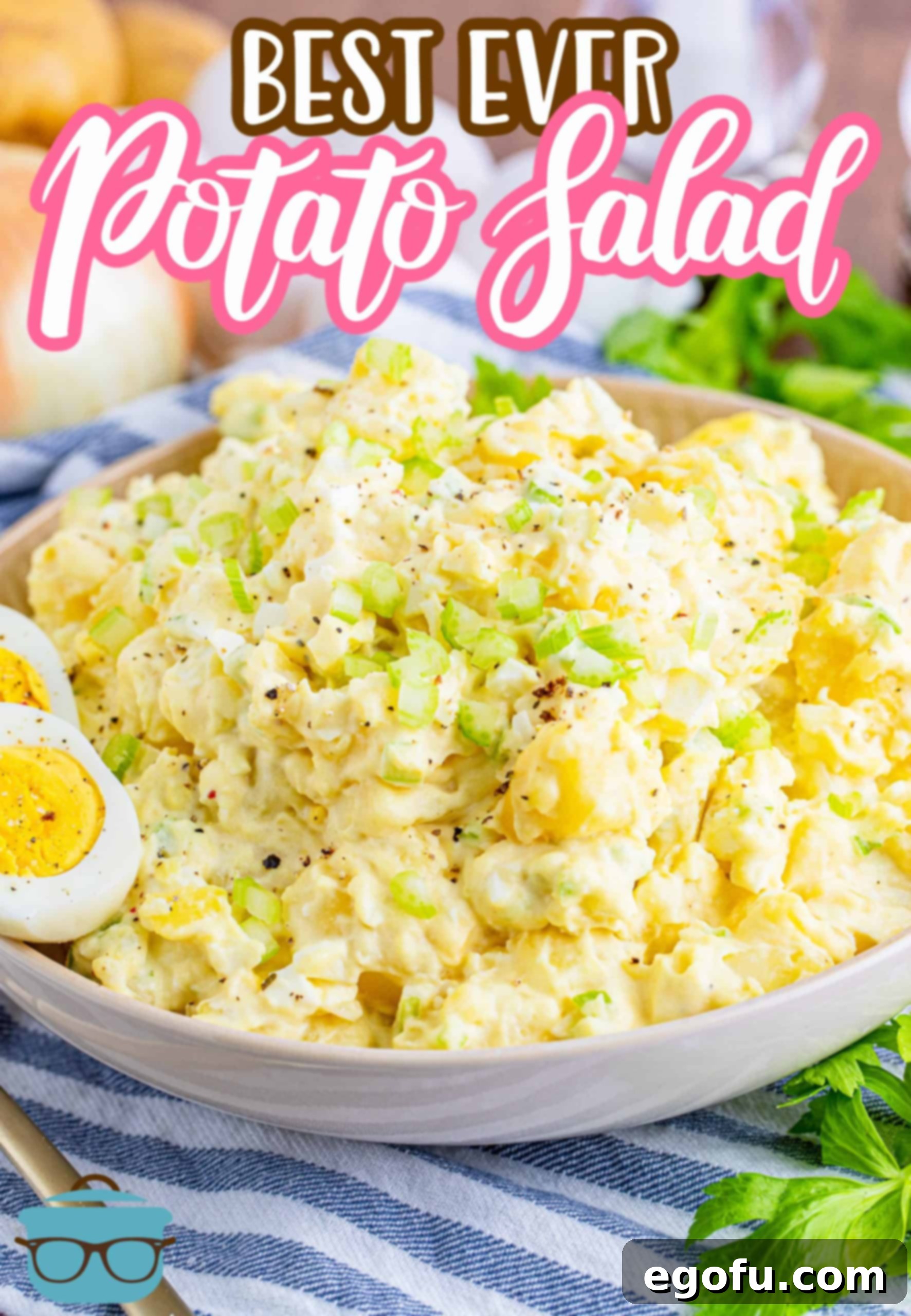 A large, shallow white bowl generously filled with the best ever potato salad, garnished with a neat slice of hard-boiled egg on the rim.