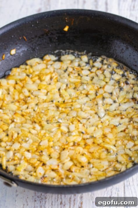 Hearty Comfort Baked Beans 11 Onions cooking in a skillet.