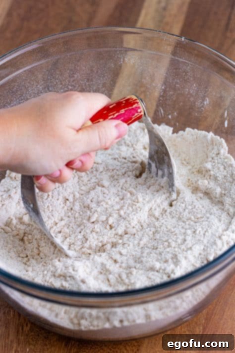 Buttery Cinnamon Raisin Biscuits 11 A hand cutting in vegetable shortening into dry biscuit ingredients in a mixing bowl.