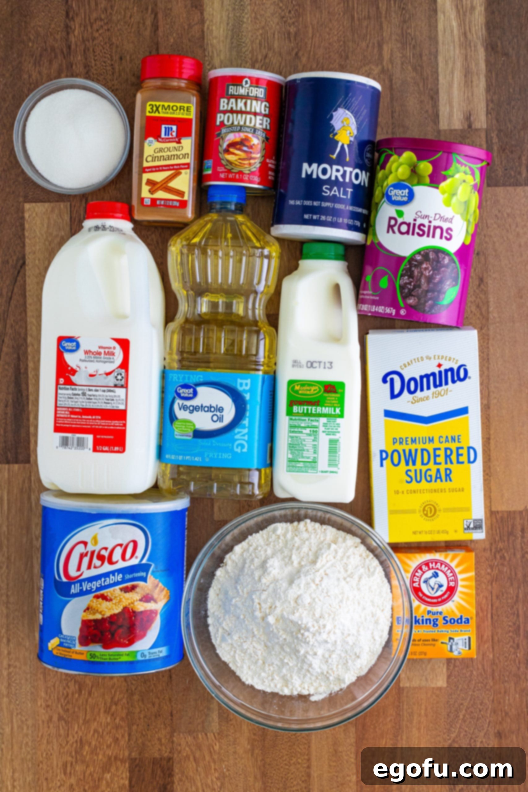 Buttery Cinnamon Raisin Biscuits 4 A collection of ingredients for Cinnamon Raisin Biscuits: all-purpose flour, powdered sugar, vegetable shortening, baking soda, vegetable oil, milk, cinnamon, salt, raisins, baking powder, and sugar.