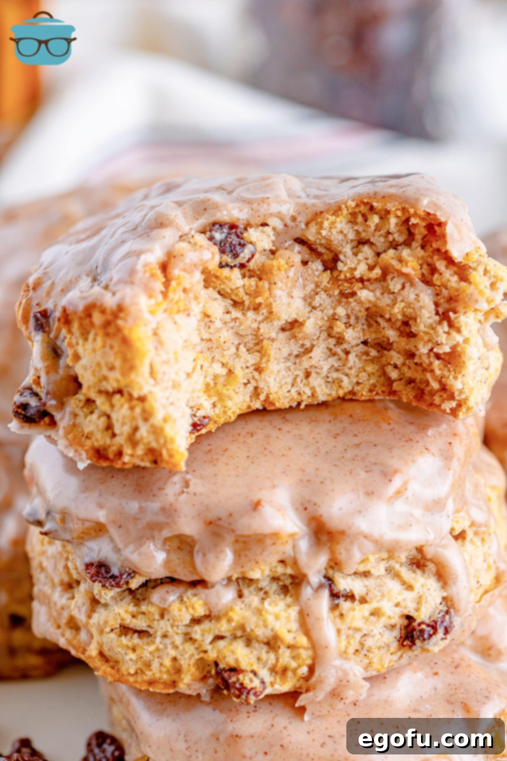 Buttery Cinnamon Raisin Biscuits 8 A stack of Cinnamon Raisin Biscuits with one biscuit having a bite taken out, showcasing its fluffy interior.