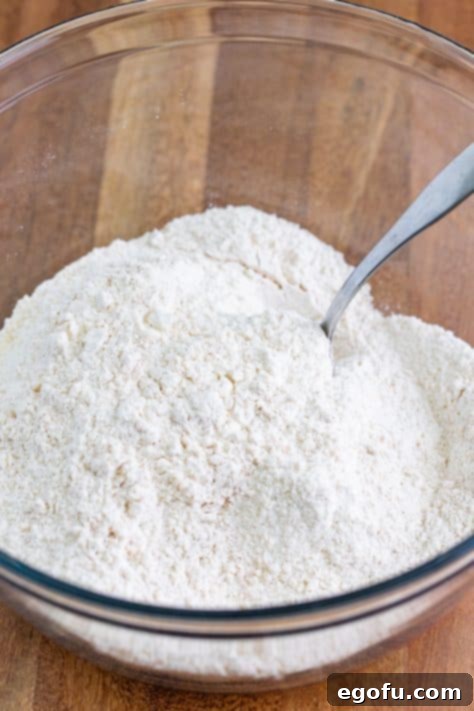Buttery Cinnamon Raisin Biscuits 10 A mixing bowl with flour, sugar, baking powder, baking soda, cinnamon, and salt.