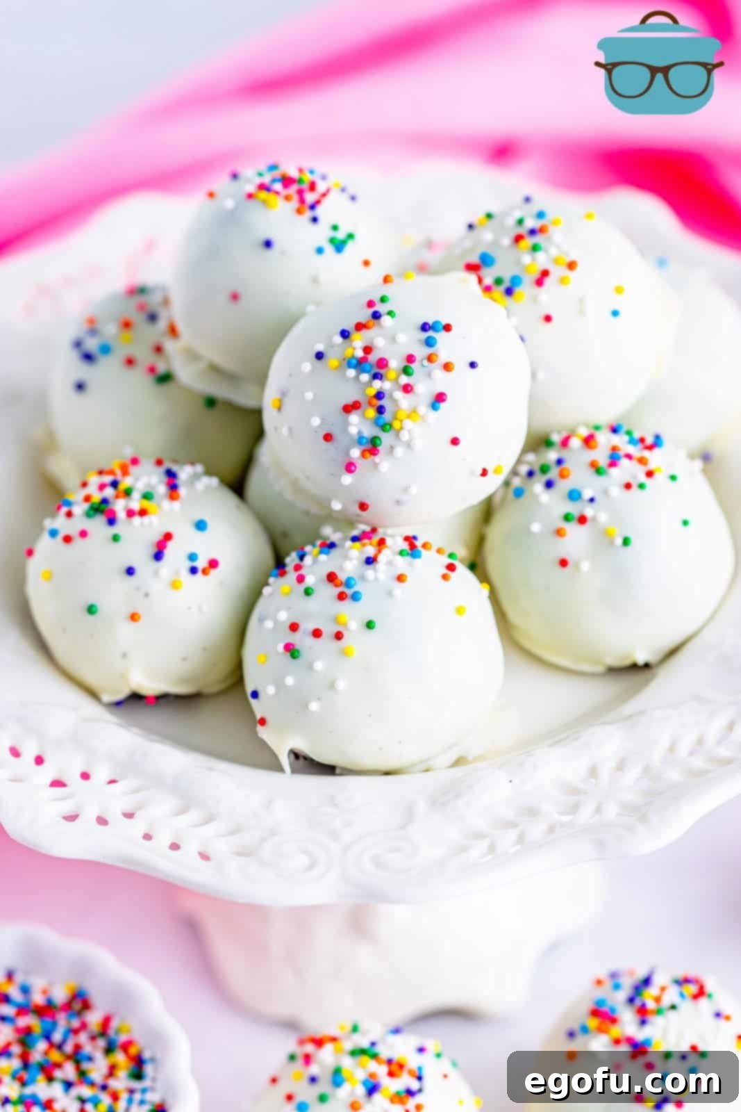 Oreo balls with sprinkles shown on a white cake stand. 
