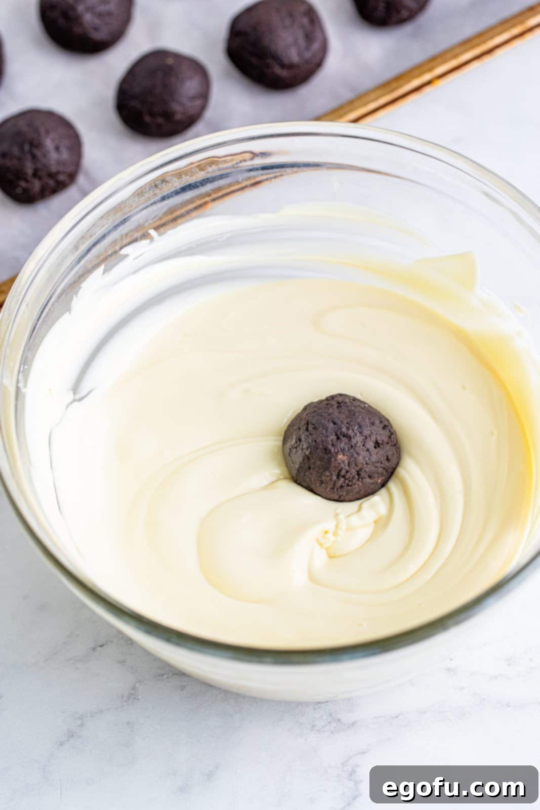 dipping cookie ball into melted white chocolate.