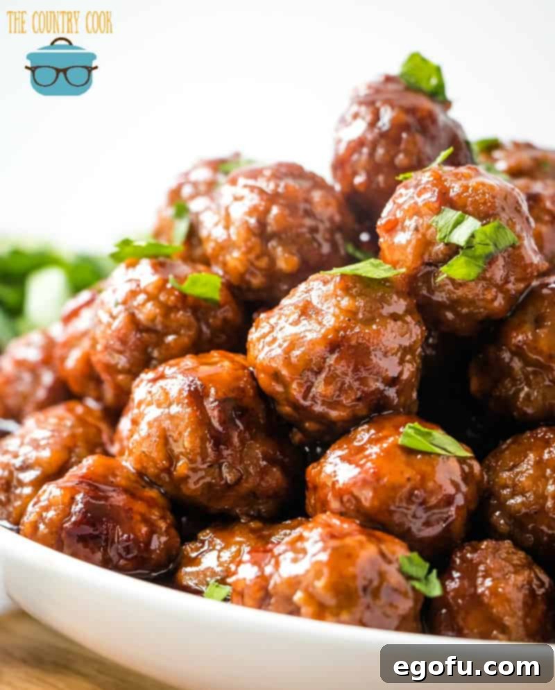 closeup photo of cooked meatballs in a white bowl with fresh chopped parsley on top.