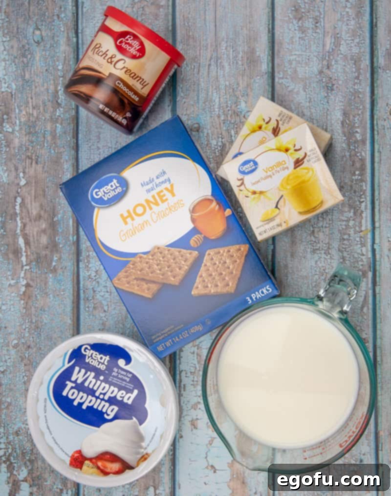 All ingredients for Eclair Cake laid out: graham crackers, instant vanilla pudding mix, milk, thawed Cool Whip, and a container of chocolate frosting.