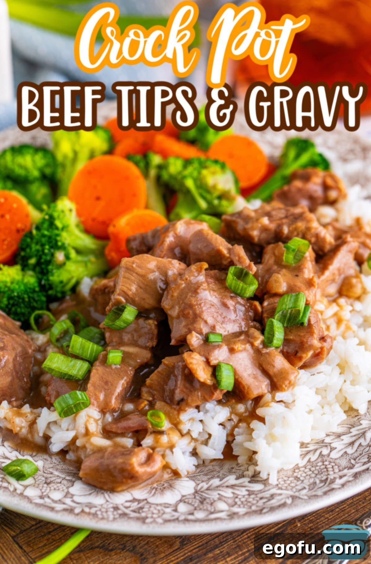 A plate with Crock Pot Beef Tips and Gravy over a bed of rice with a side of carrots and broccoli, ready to be enjoyed.