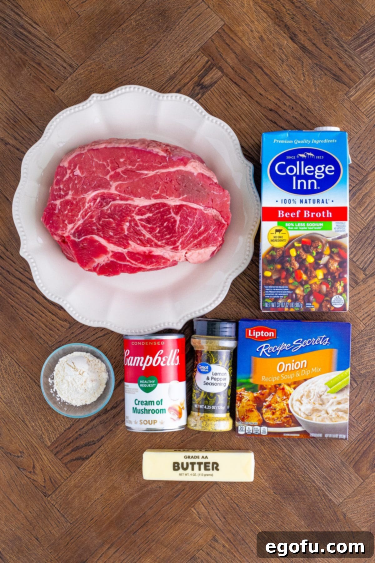 Individual ingredients laid out: beef chuck, beef broth, butter, onion dry mix, flour, cream of mushroom soup, lemon pepper, and salt.