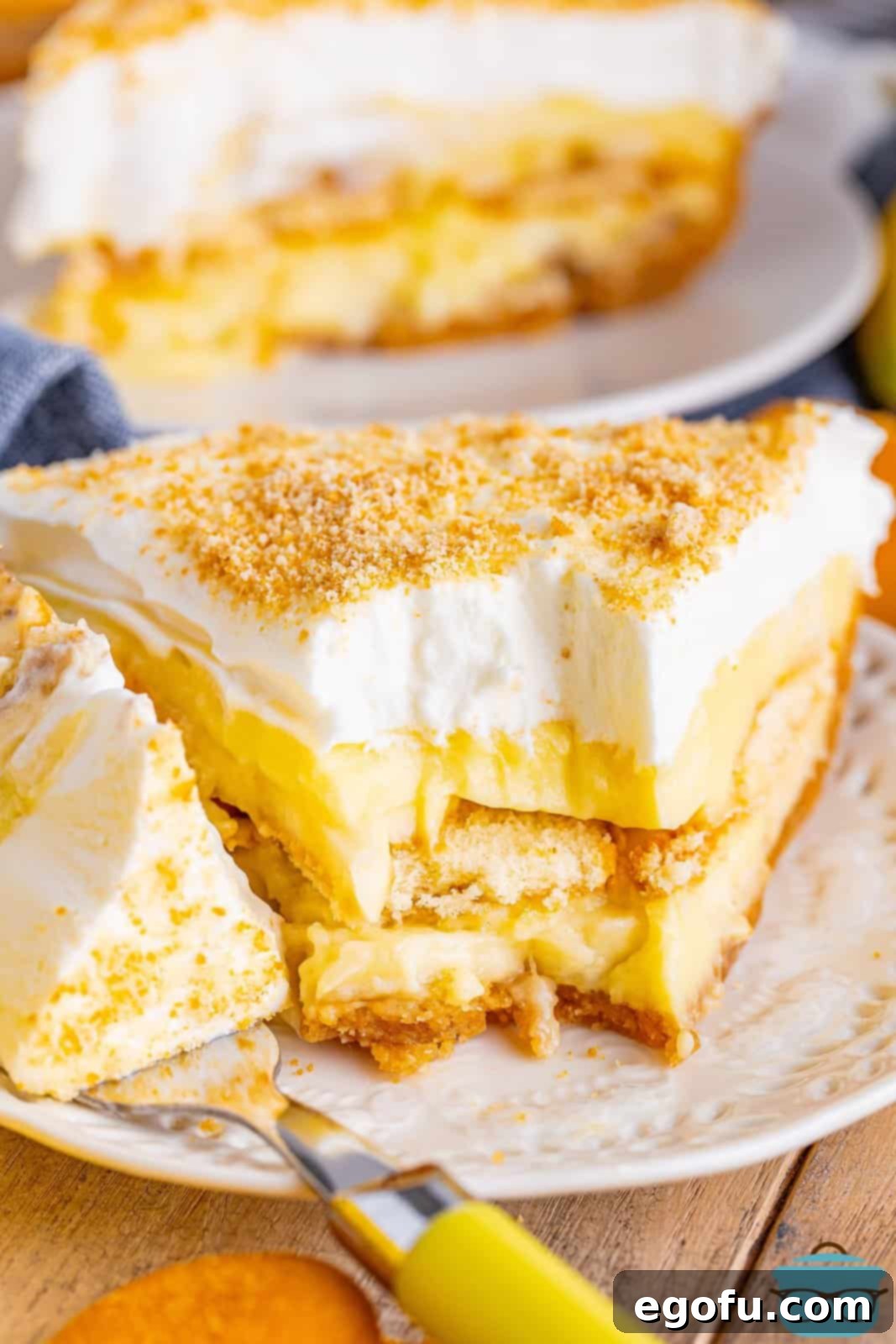 Golden Banana Dream Pie 13 A delicious slice of Banana Pudding Pie on a plate, with a small bite removed, inviting you to enjoy its creamy layers and crunchy crust.