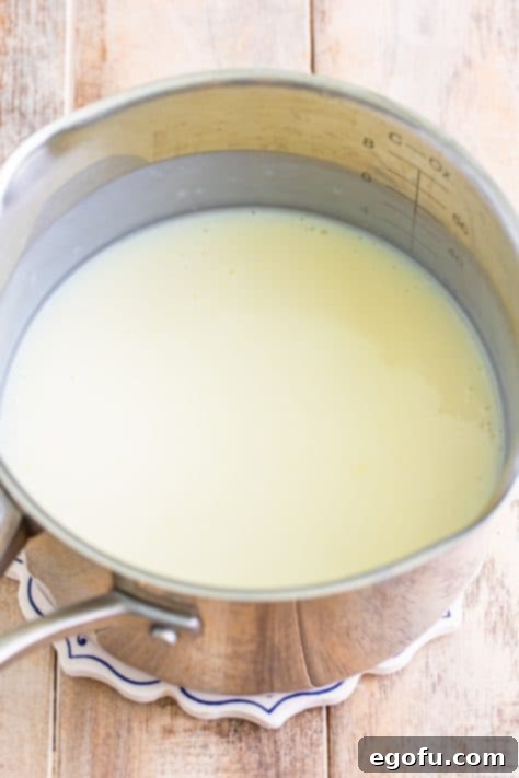 Golden Banana Dream Pie 19 Milk being added and whisked into the dry ingredients in a saucepan, thickening into a creamy mixture.