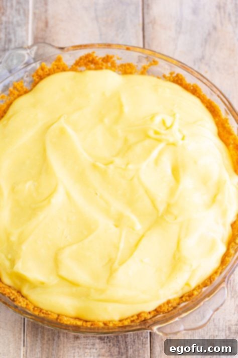 Golden Banana Dream Pie 26 The final layer of smooth, creamy pudding being spread over the bananas and wafers, completing the pie's filling.