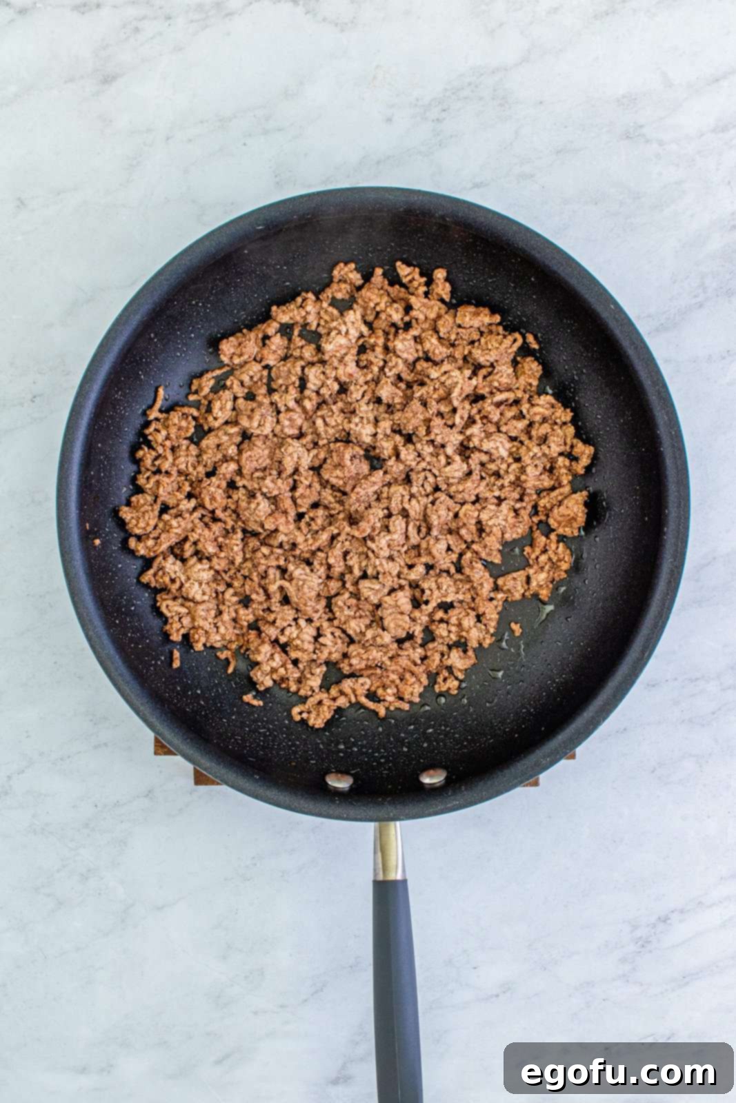 Doritos Fiesta Salad 5 Ground beef browning in a skillet, being broken apart with a wooden spoon.