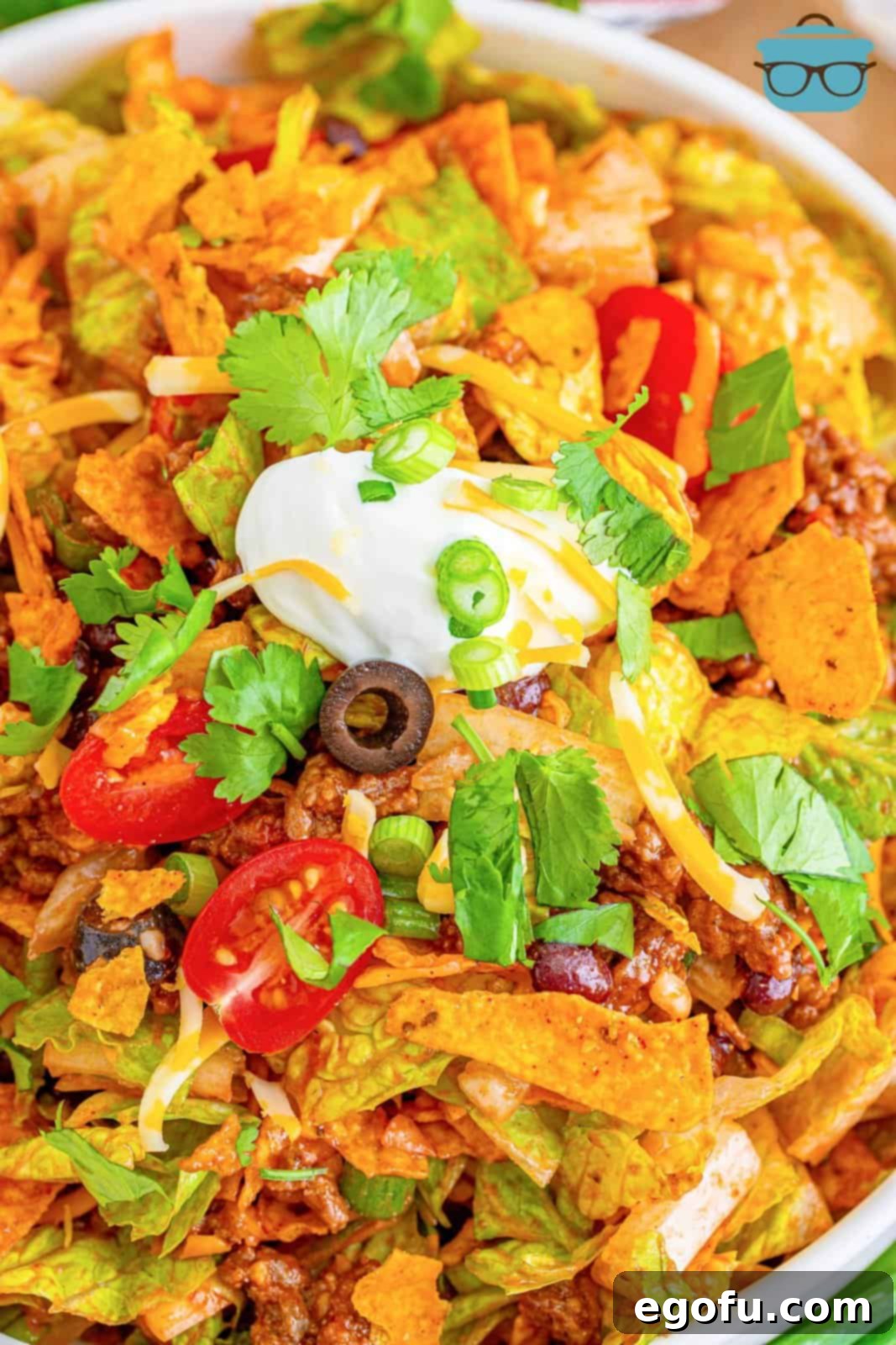 Doritos Fiesta Salad 9 An individual white bowl filled with Doritos Taco Salad, neatly topped with a dollop of sour cream.