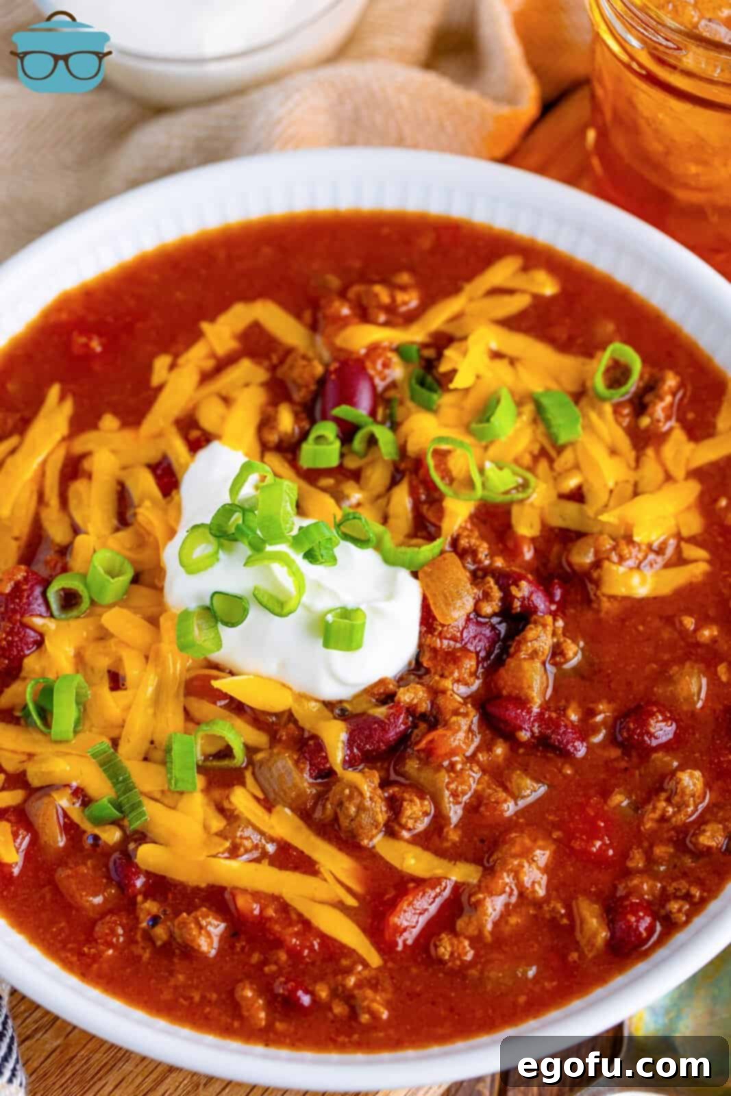 an overhead photo of a bowl of chili topped with cheese and sour cream. 