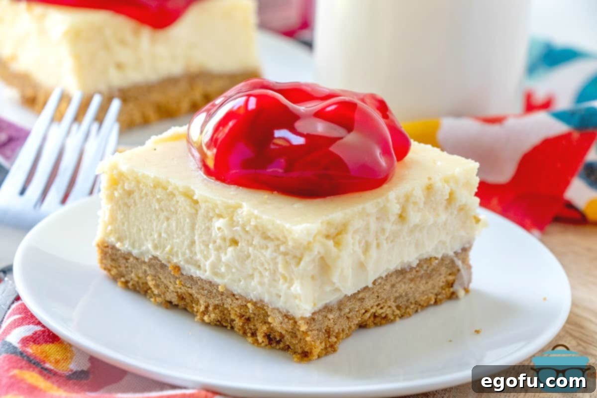 A perfectly sliced Cherry Cheesecake Bar resting on a pristine white plate, showcasing its creamy layers and vibrant cherry topping.