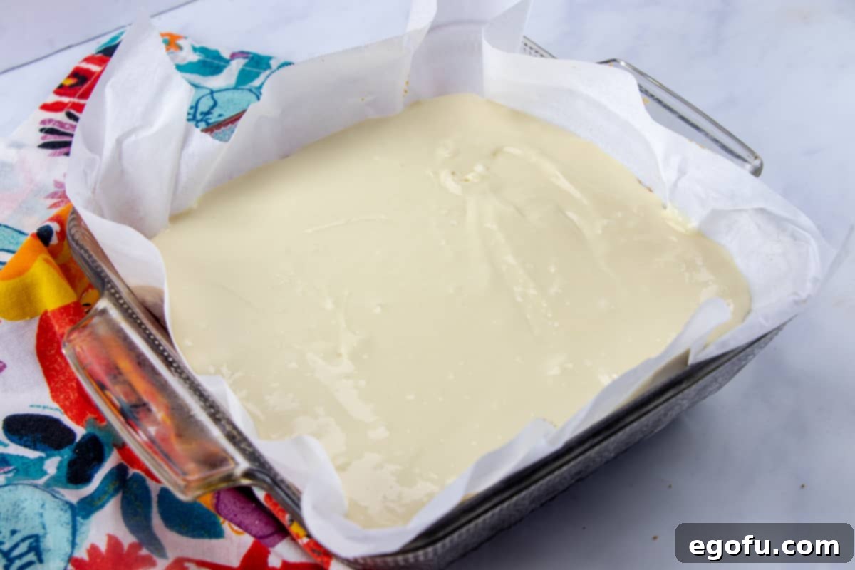 Smooth cheesecake filling elegantly poured over the golden-brown graham cracker crust, nestled in a baking pan, ready for its final bake.