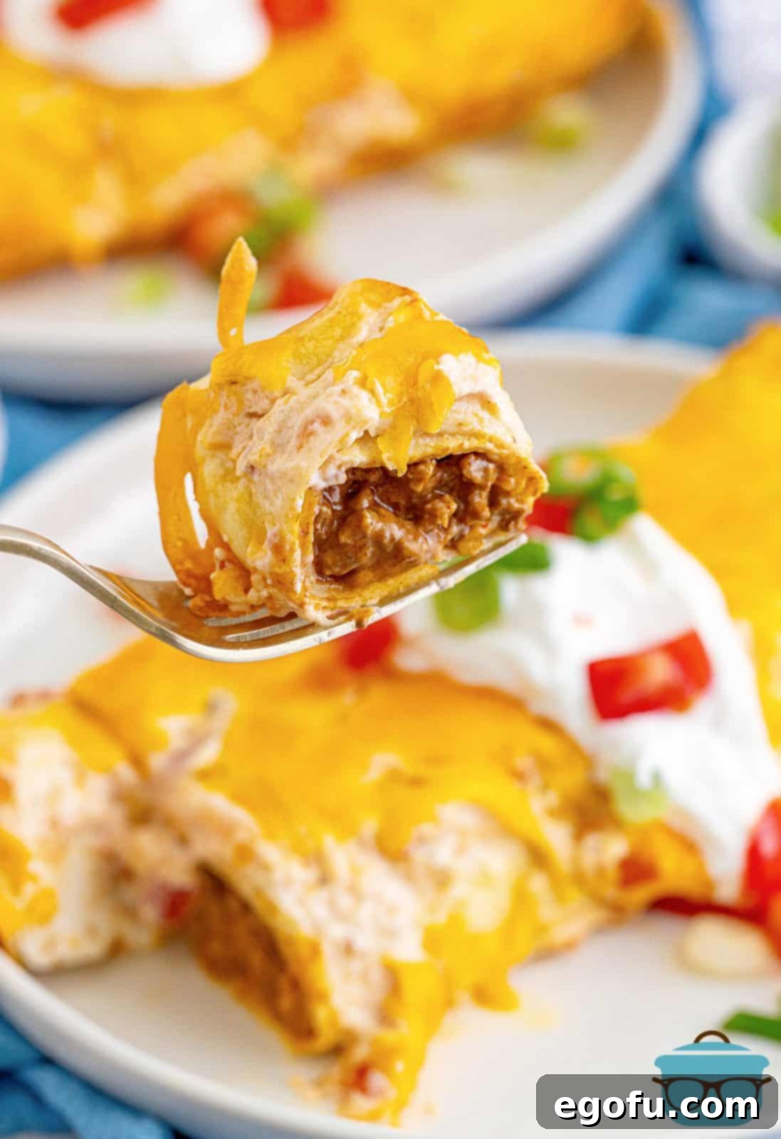 Fork holding up bite out of Ground Beef Enchiladas.