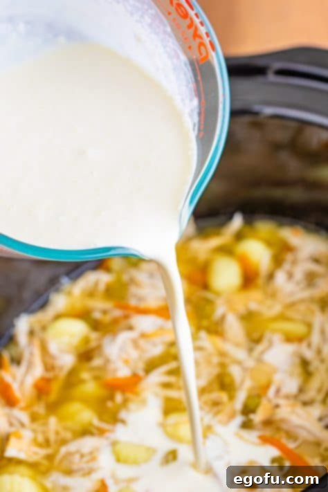 Creamy Slow Cooker Olive Garden Chicken Gnocchi Soup 13 Heavy cream and cornstarch being added to a soup in a slow cooker.