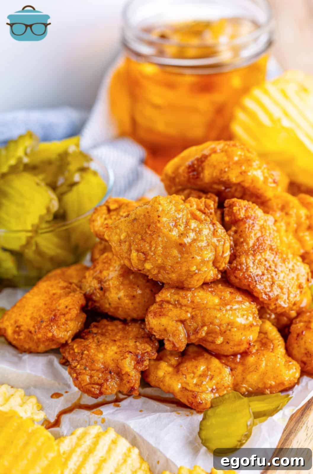 Crispy Air Fryer Nashville Hot Chicken Nuggets with sliced dill pickles and potato chips, alongside a glass of iced tea.