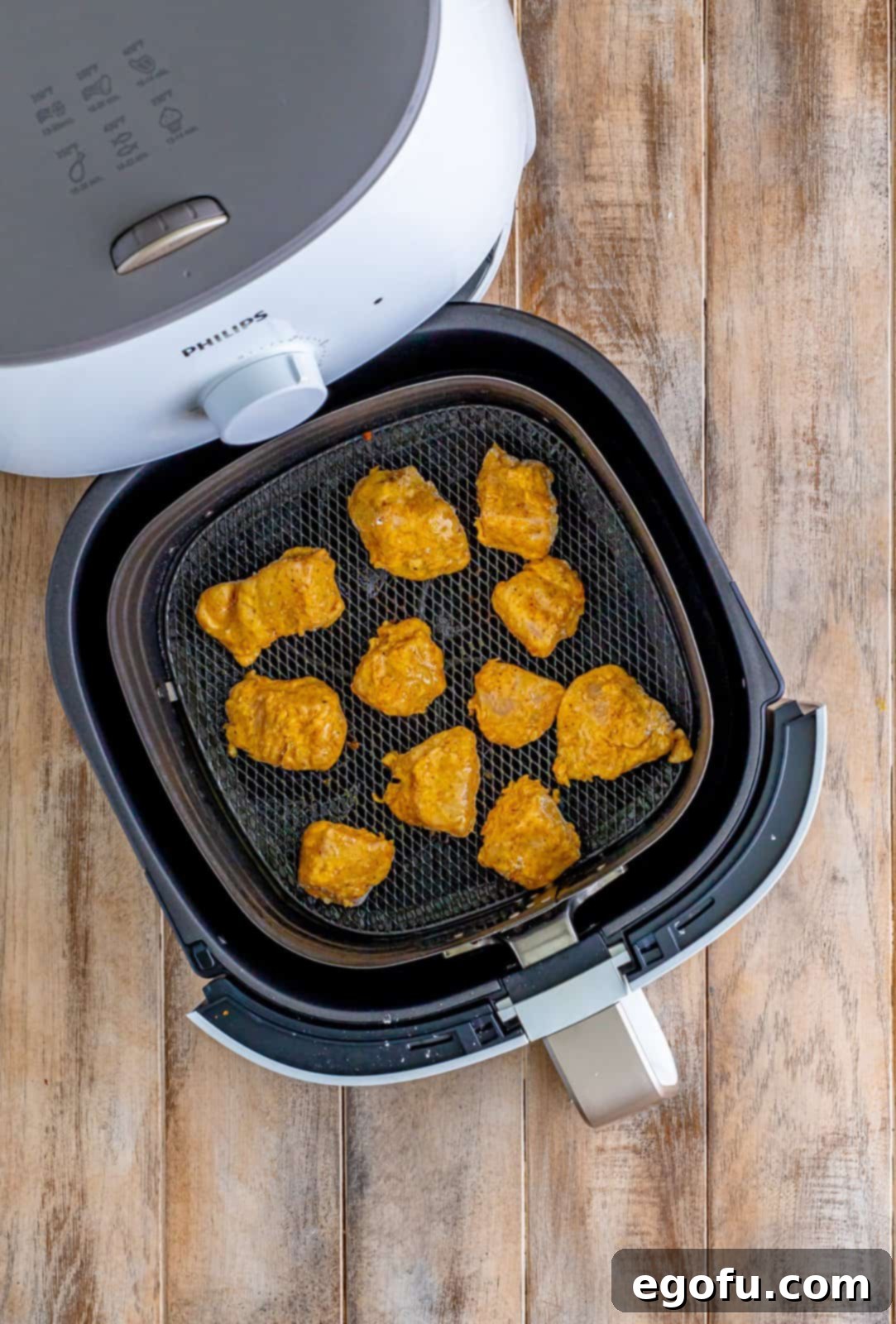 Coated chicken breasts arranged in a single layer within an air fryer basket, ready for cooking.