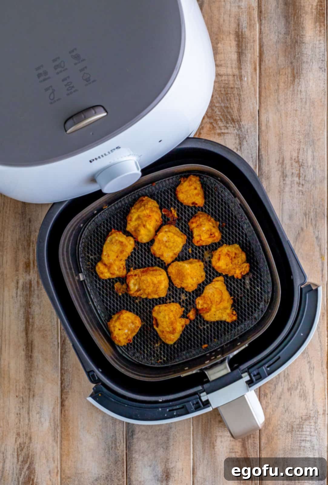 Fully cooked, golden-brown chicken nuggets resting in the bottom of an air fryer basket after being perfectly air-fried.