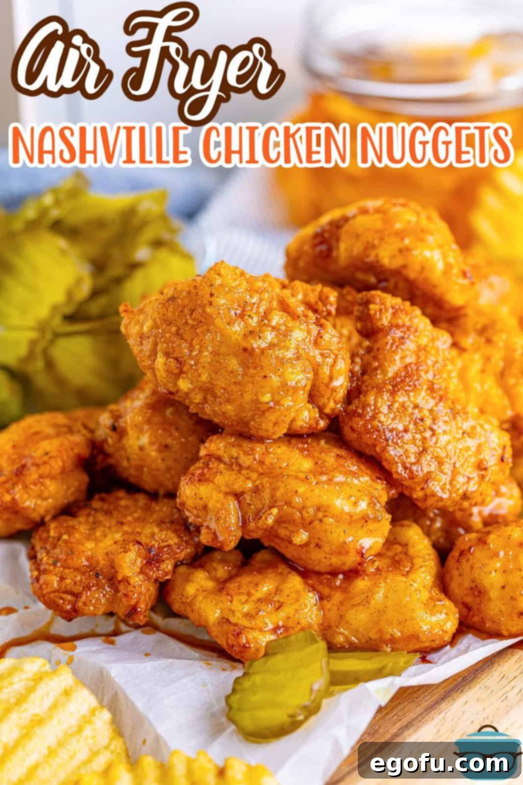 A delectable stack of Air Fryer Nashville Hot Chicken Nuggets served with a side of crispy ridge potato chips and tangy dill pickles.