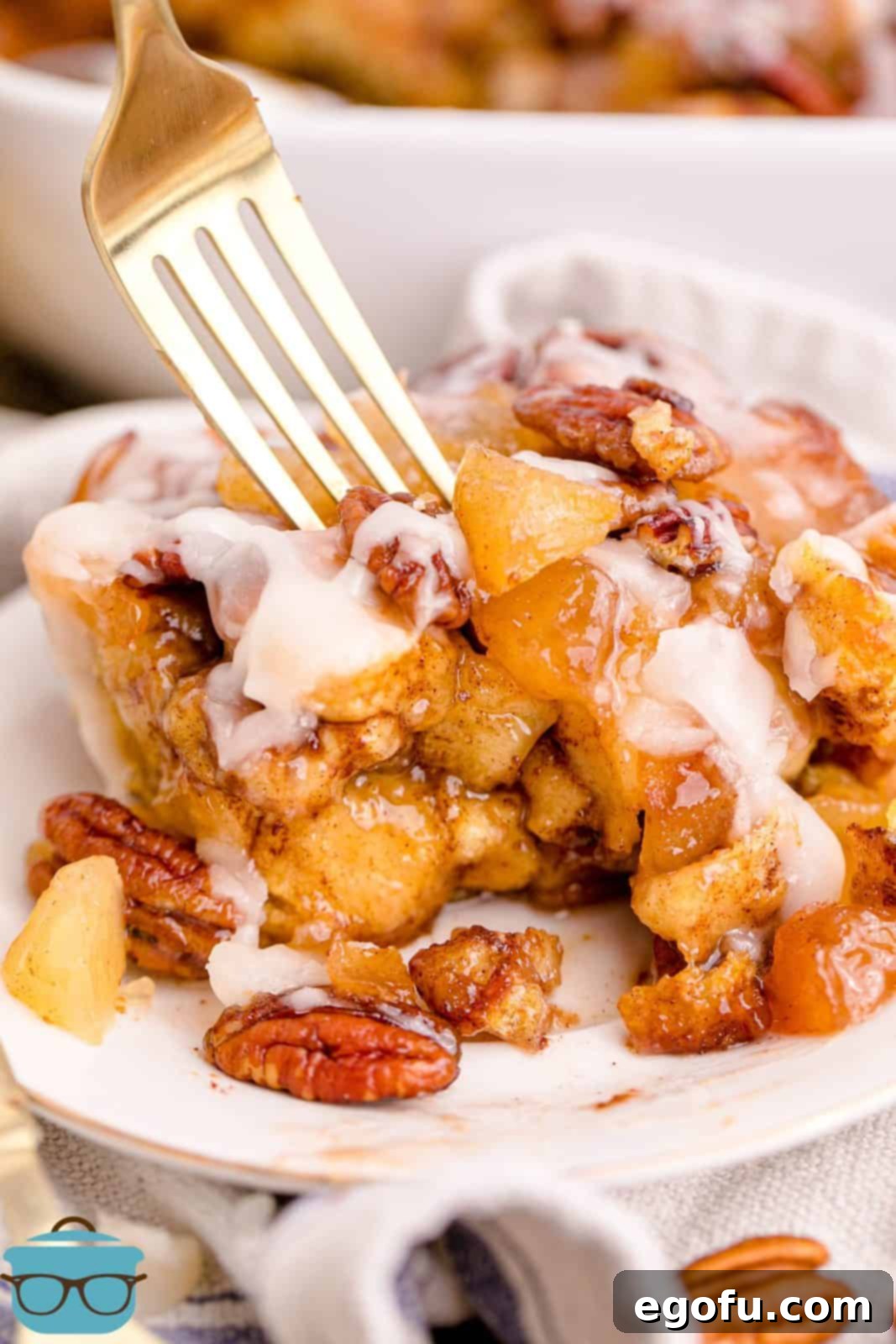 Gooey Cinnamon Roll Delight 14 Some Cinnamon Roll Casserole on white plate with fork.