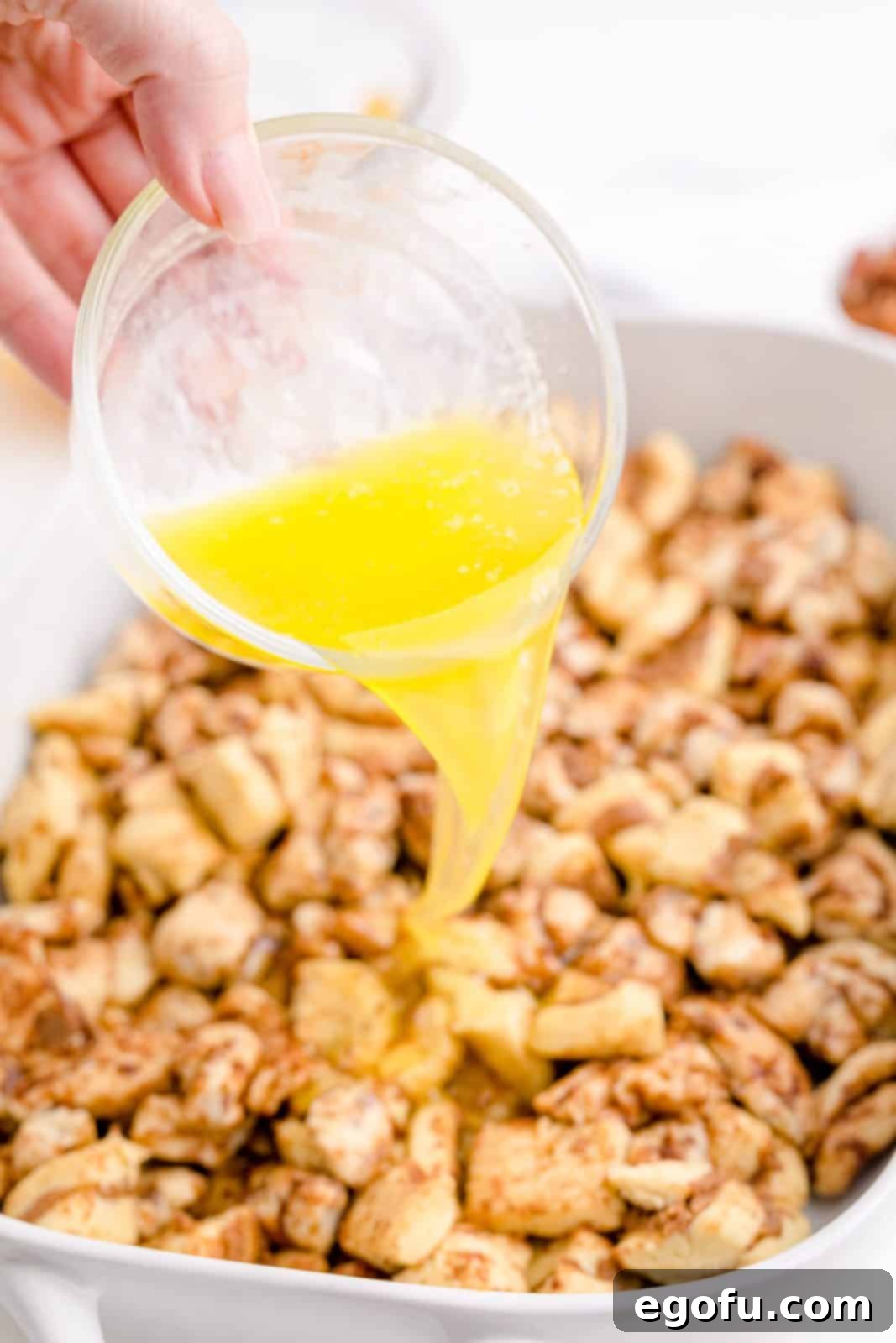 Gooey Cinnamon Roll Delight 7 Melted butter being poured over cinnamon rolls.