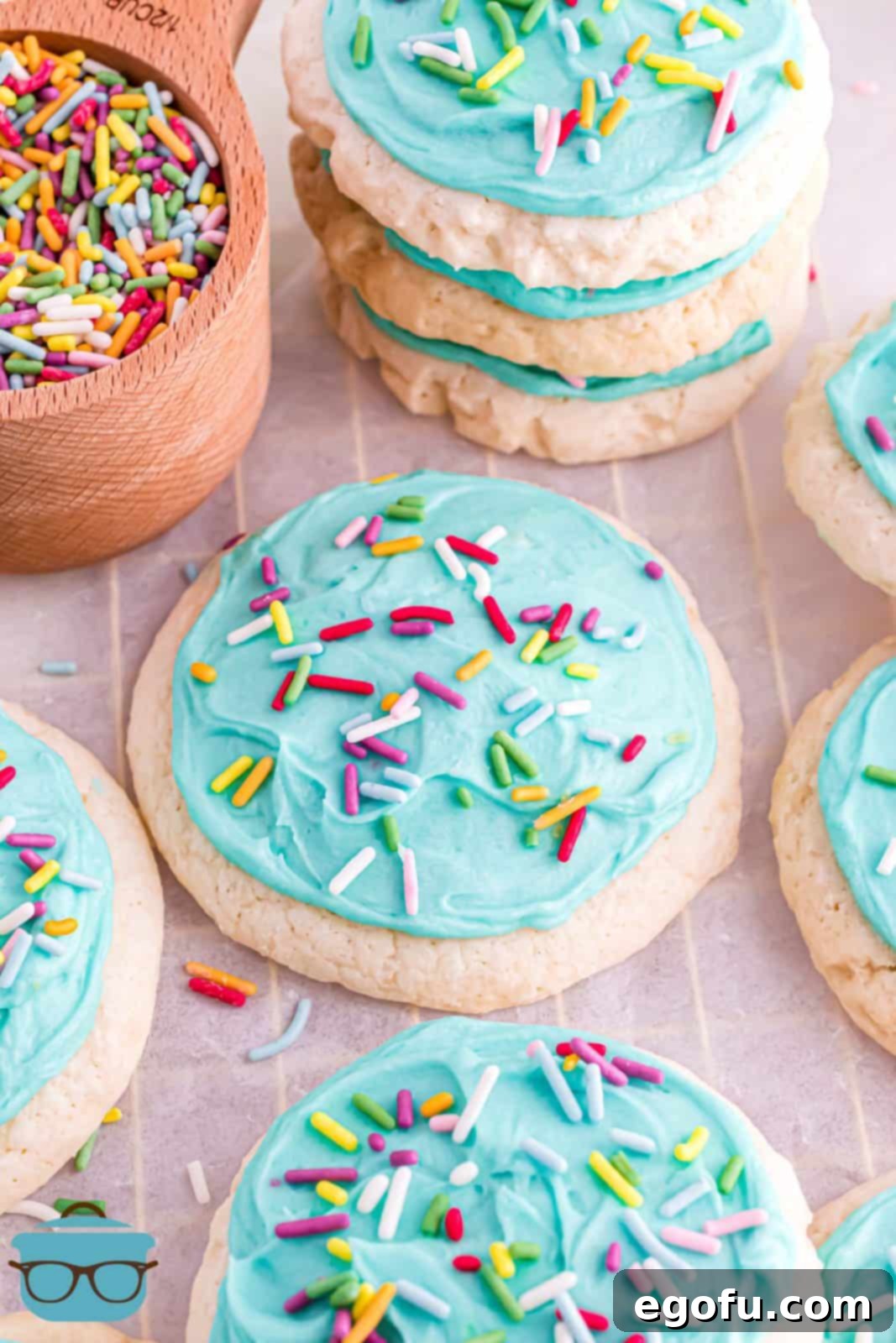 Copycat Lofthouse Cookies on board with some stacked and a bowl of sprinkles.