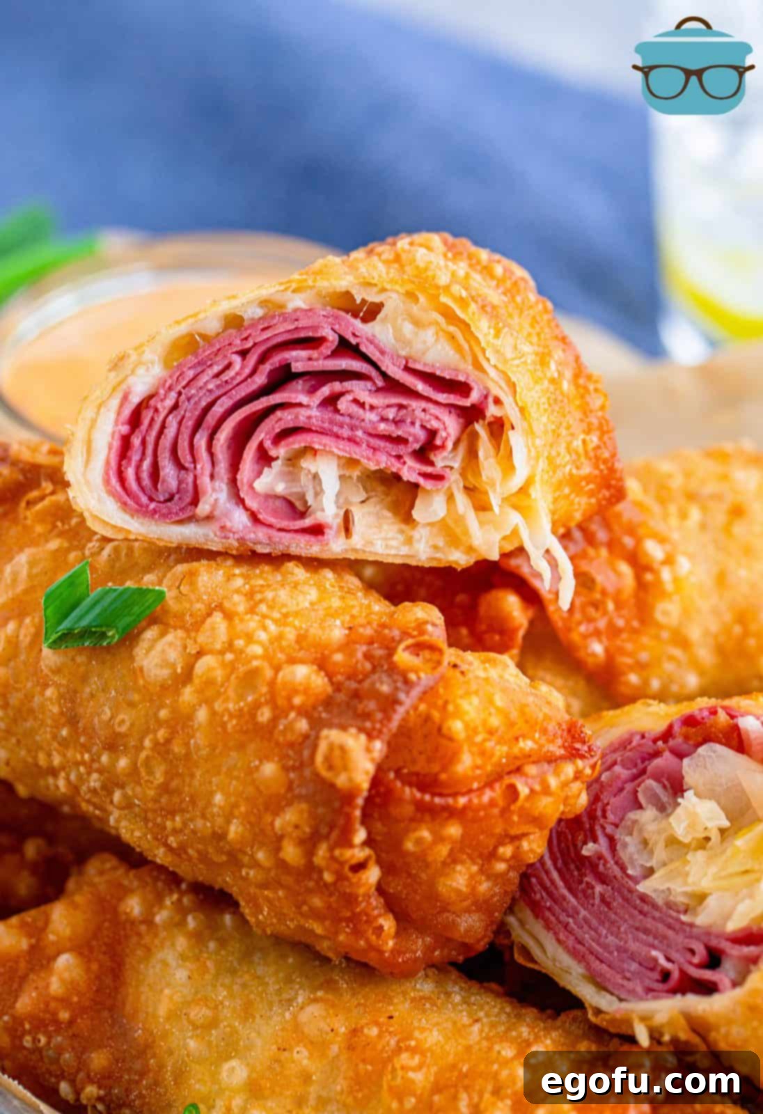 Close up of one Reuben Egg Roll cut in half showing the inside, revealing layers of corned beef, swiss cheese, and sauerkraut.