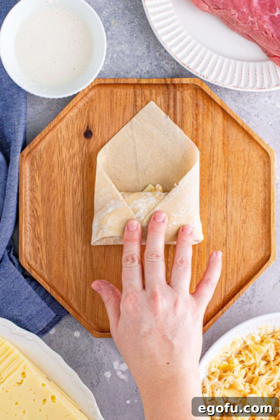 Both side corners of the egg roll wrapper meticulously folded inwards, creating a compact and secure package around the filling.