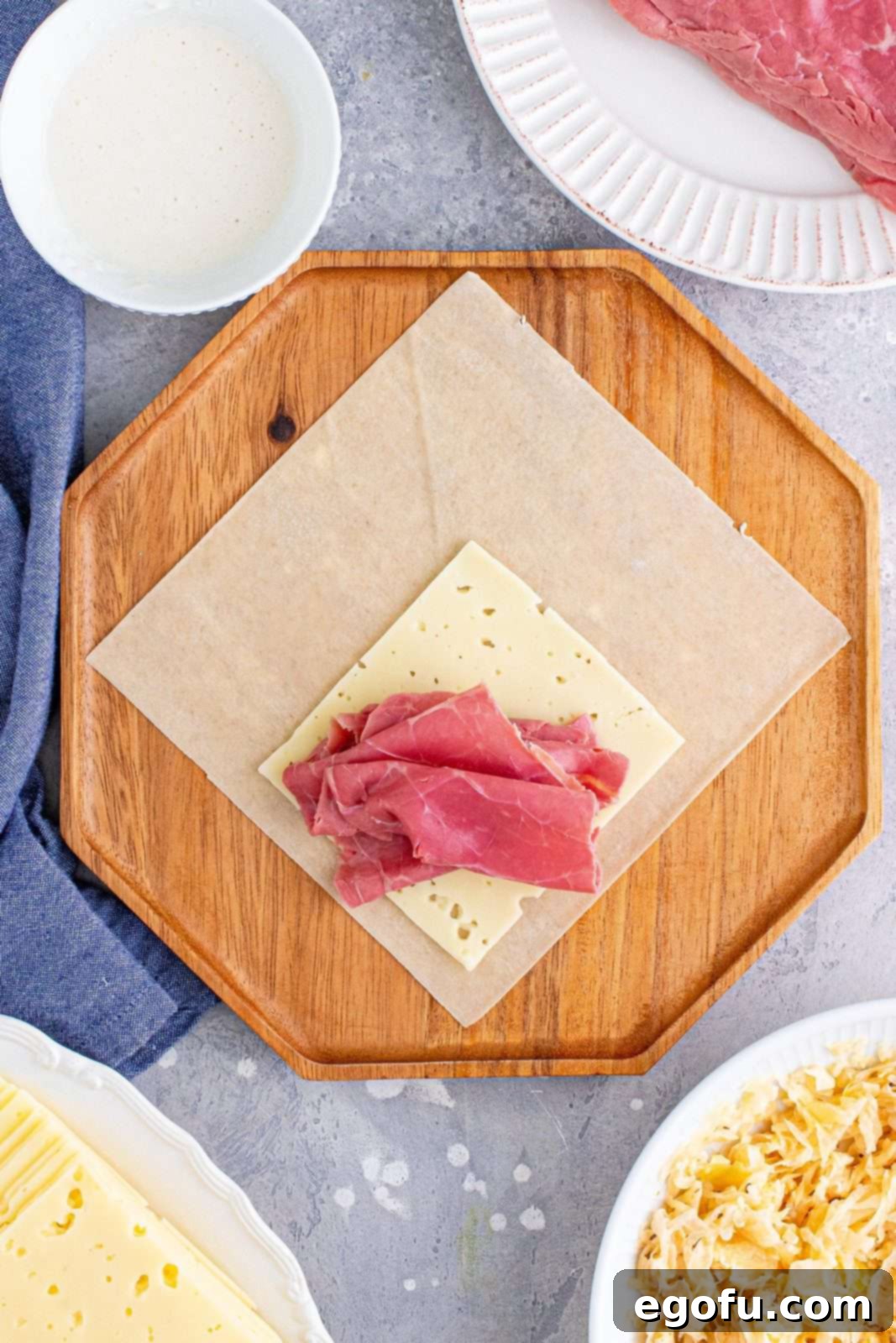 Two slices of tender corned beef carefully arranged on top of the Swiss cheese layer on the egg roll wrapper.