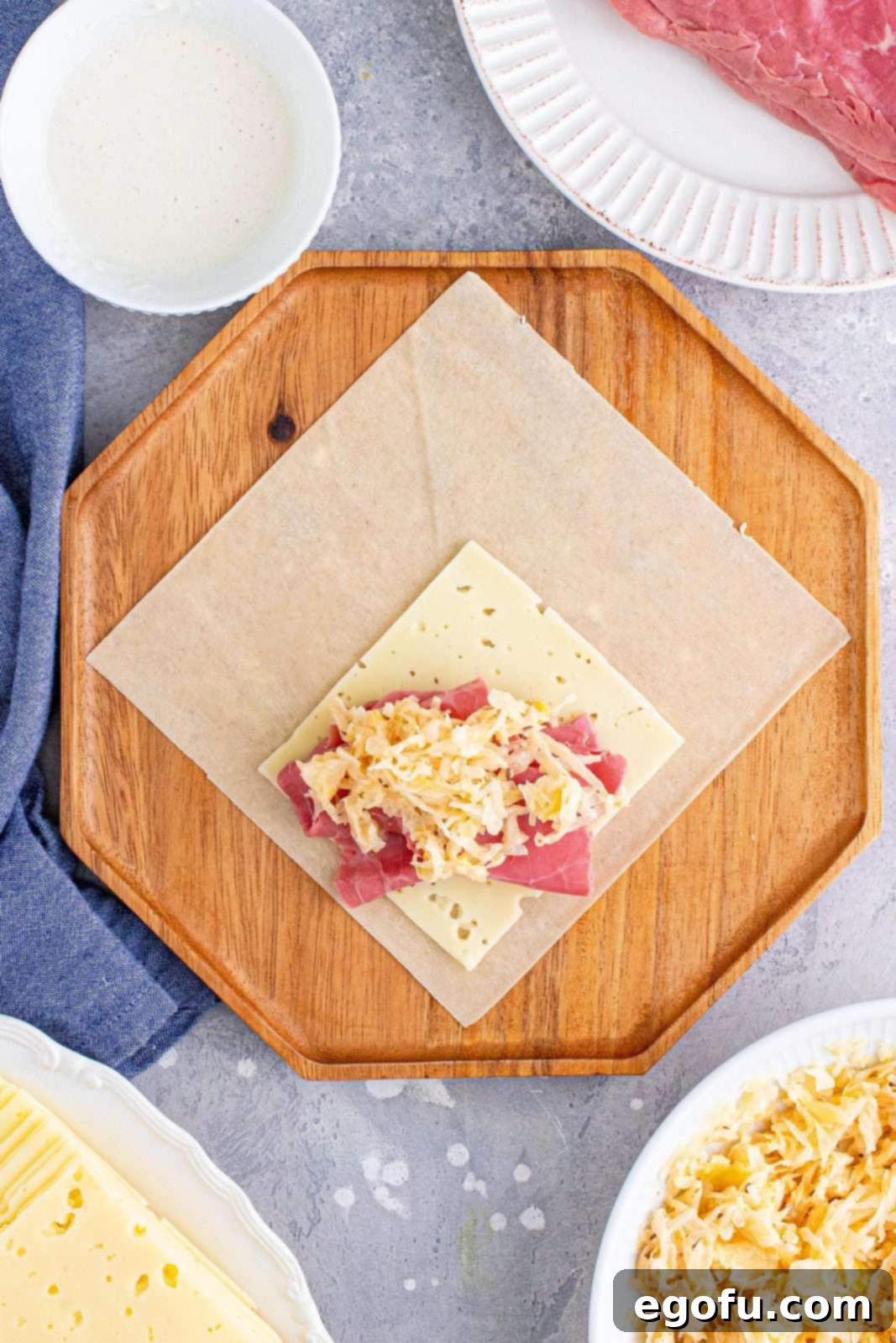 A generous dollop of the sauerkraut mixture, perfectly seasoned with Thousand Island dressing, placed atop the corned beef layer on the egg roll wrapper.