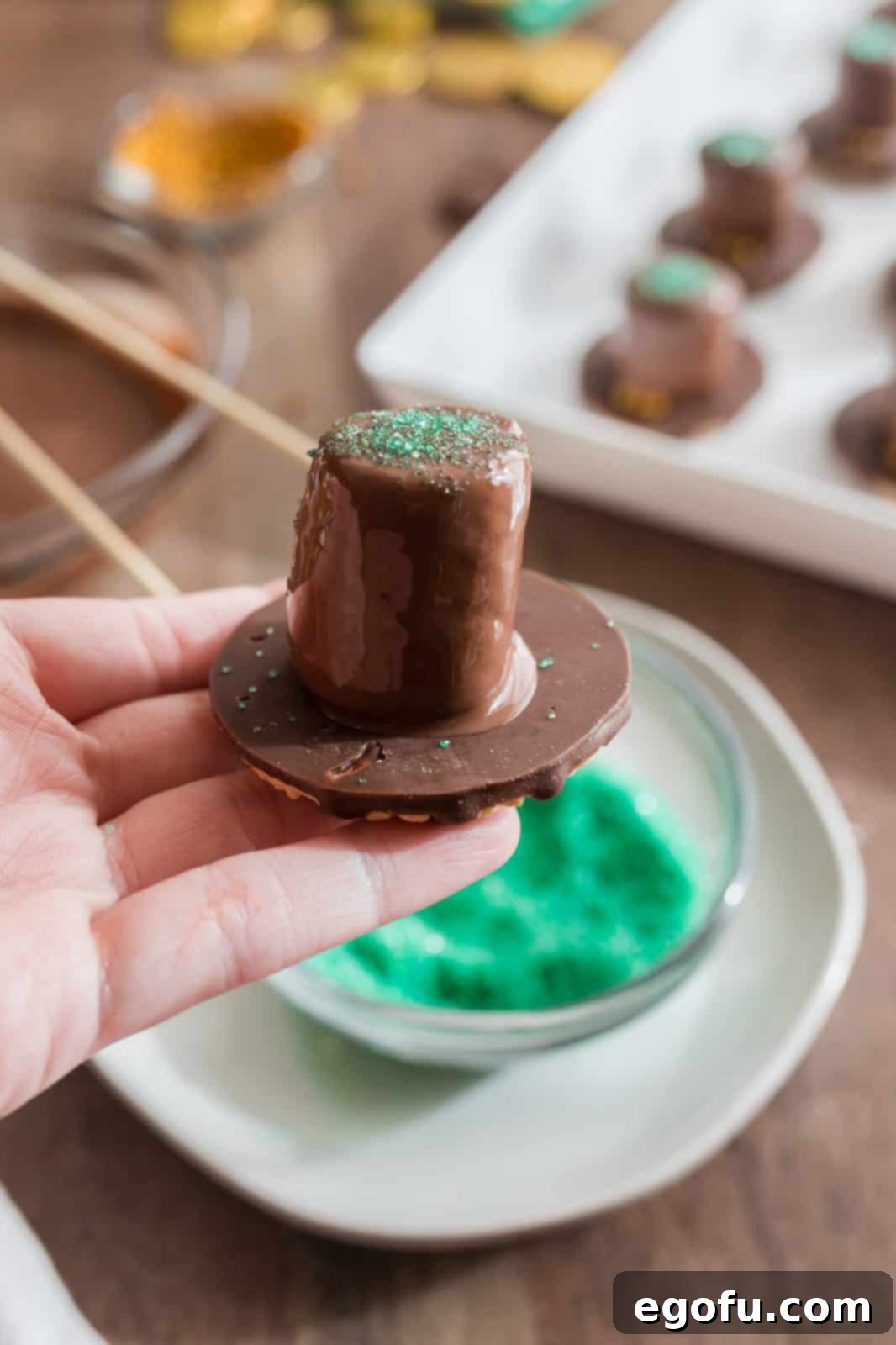 Chocolate covered marshmallow placed on fudge-striped cookie and decorated with green sprinkes.