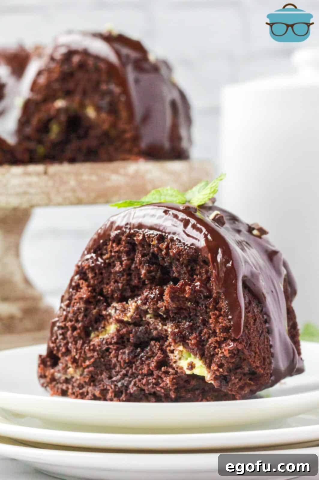 Slice of Mint Chocolate Bundt Cake on white plate with whole cake in background.