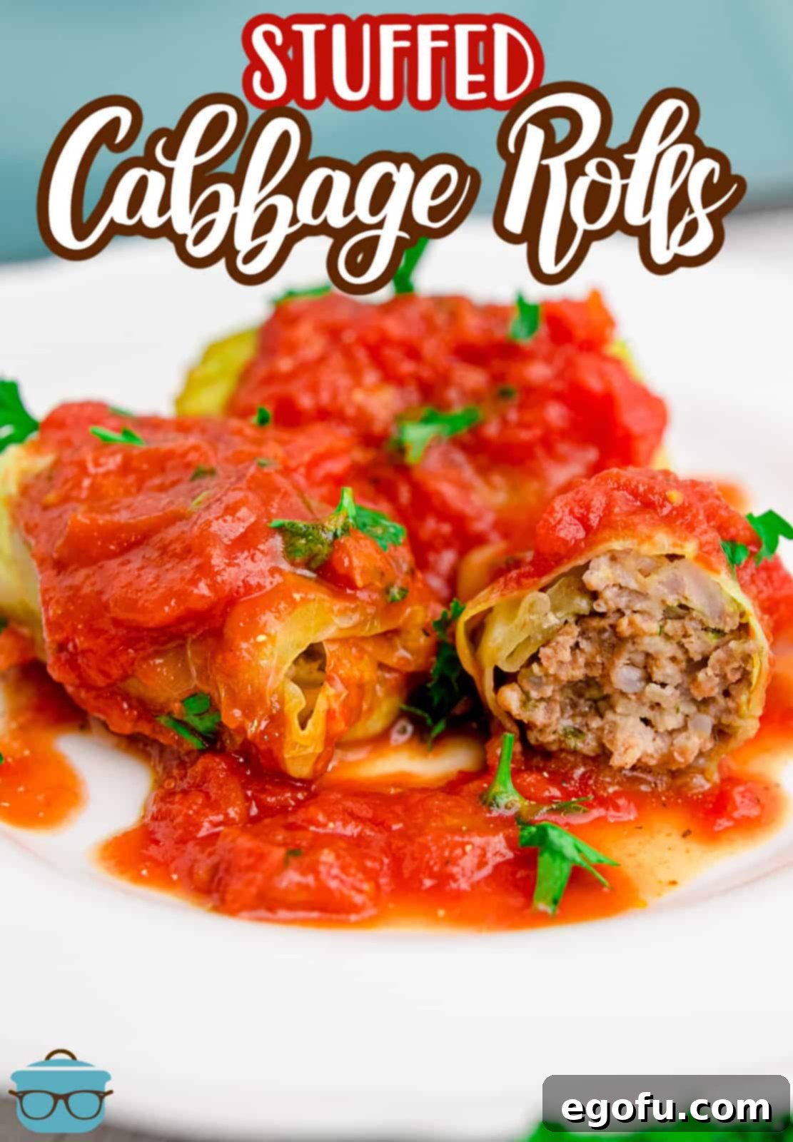 a cabbage roll cut in half to show the inside on a white plate with tomato sauce.