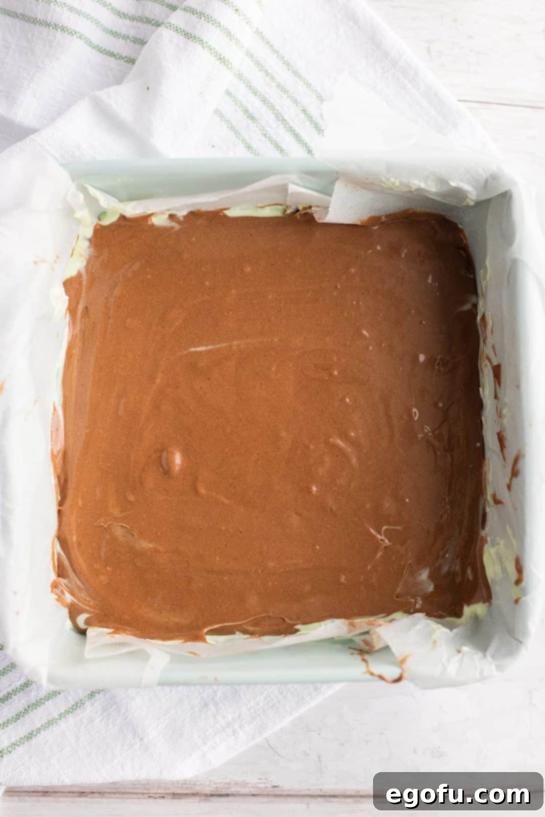 Remaining brownie mixture added over the mint cream cheese filling, ready for baking.