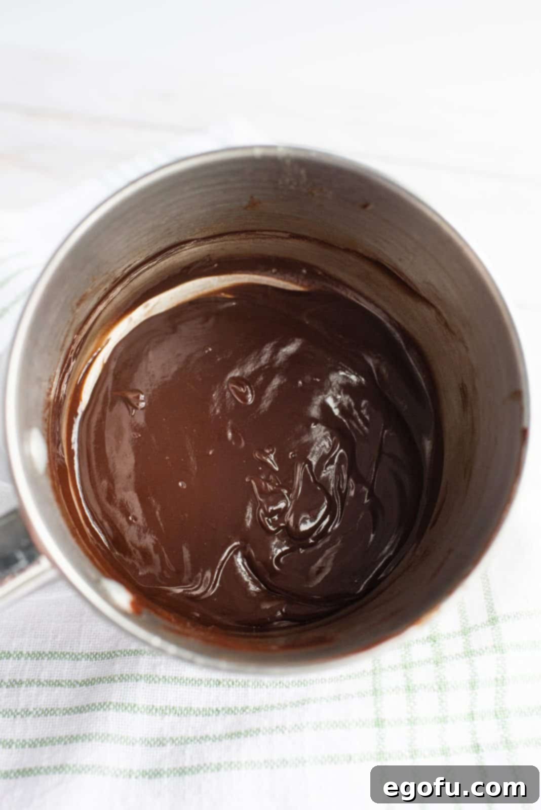 Chocolate frosting ingredients mixed together in a bowl, showing its smooth consistency.