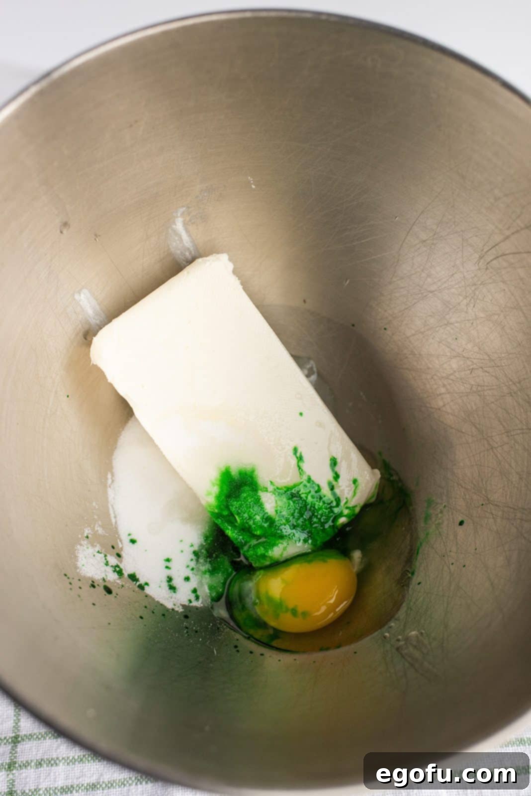 Cream cheese, sugar, peppermint extract, and egg being beaten in a stand mixer bowl for the filling.
