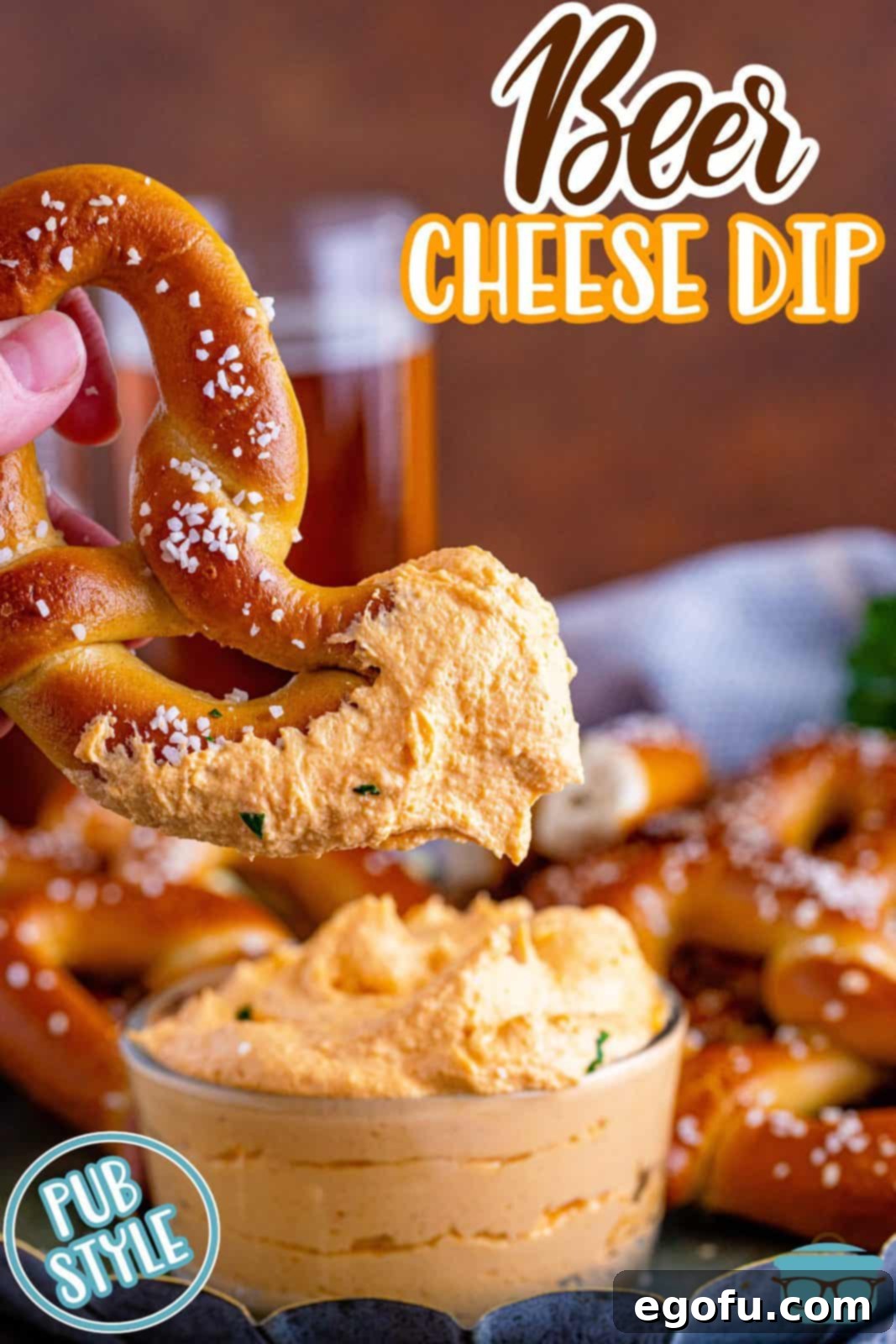 Pinterest image of hand holding up a pretzel dipped in Beer Cheese Dip.