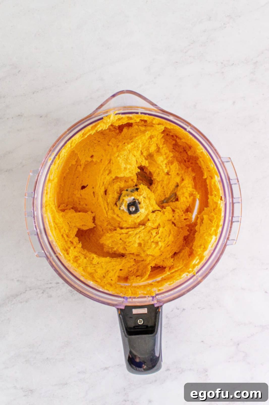 Processed ingredients in food processor, showing a smooth, thick cheese mixture.